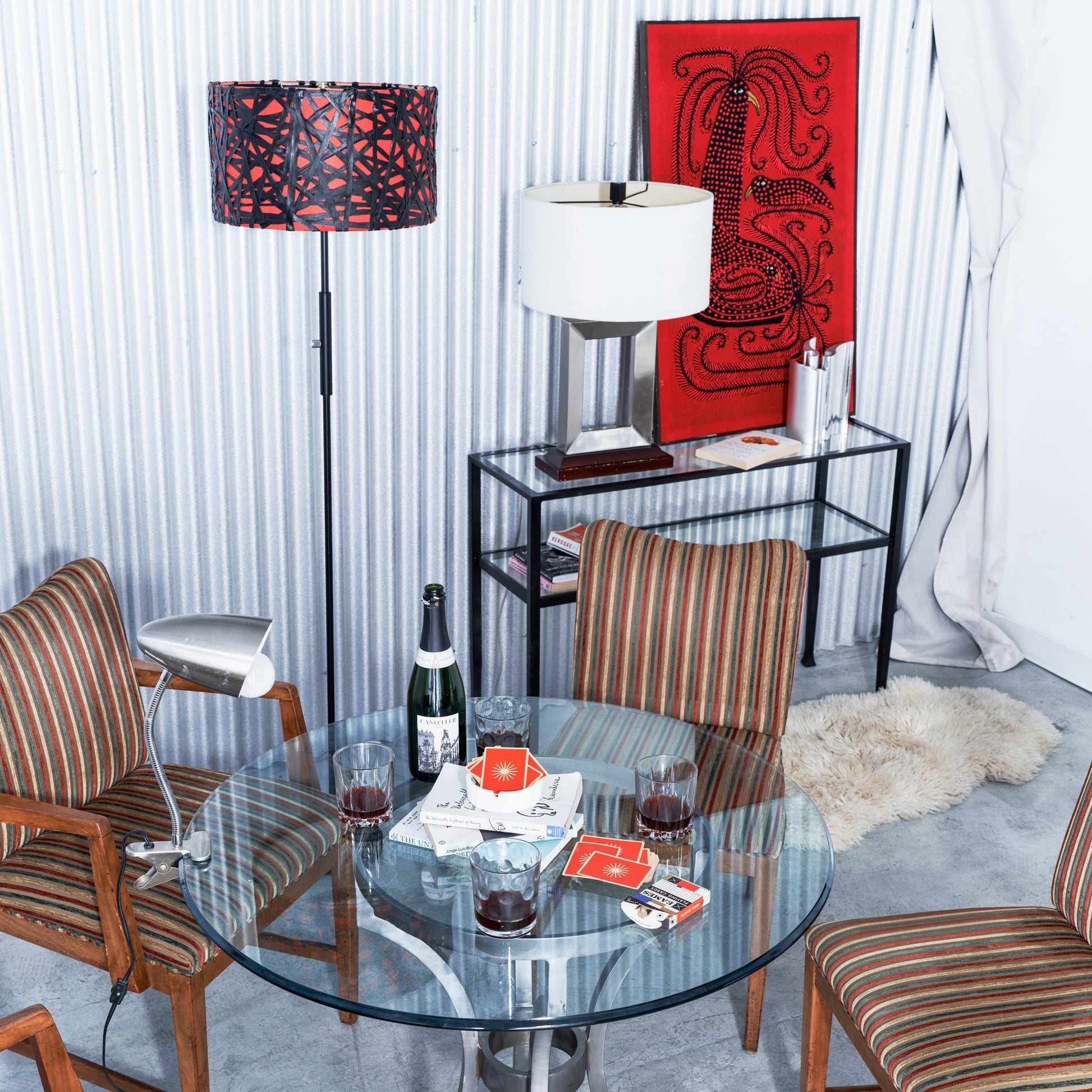 Dining room with round glass table, striped chairs, and decorative elements.