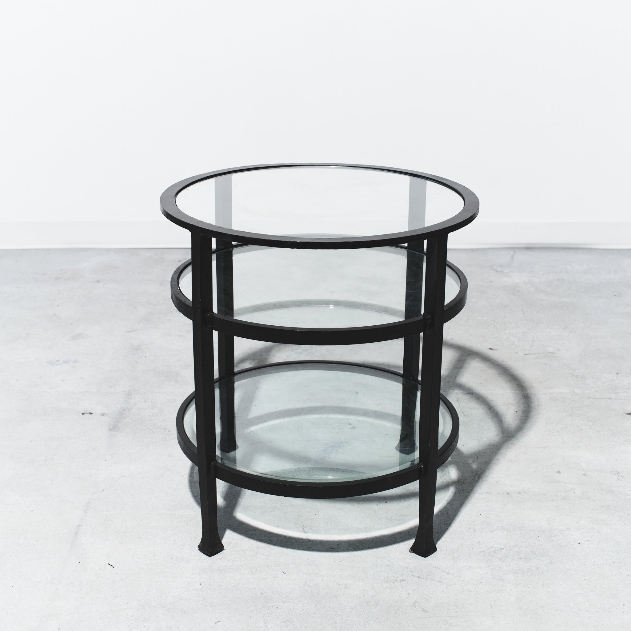 Round glass table with black metal frame on a white background