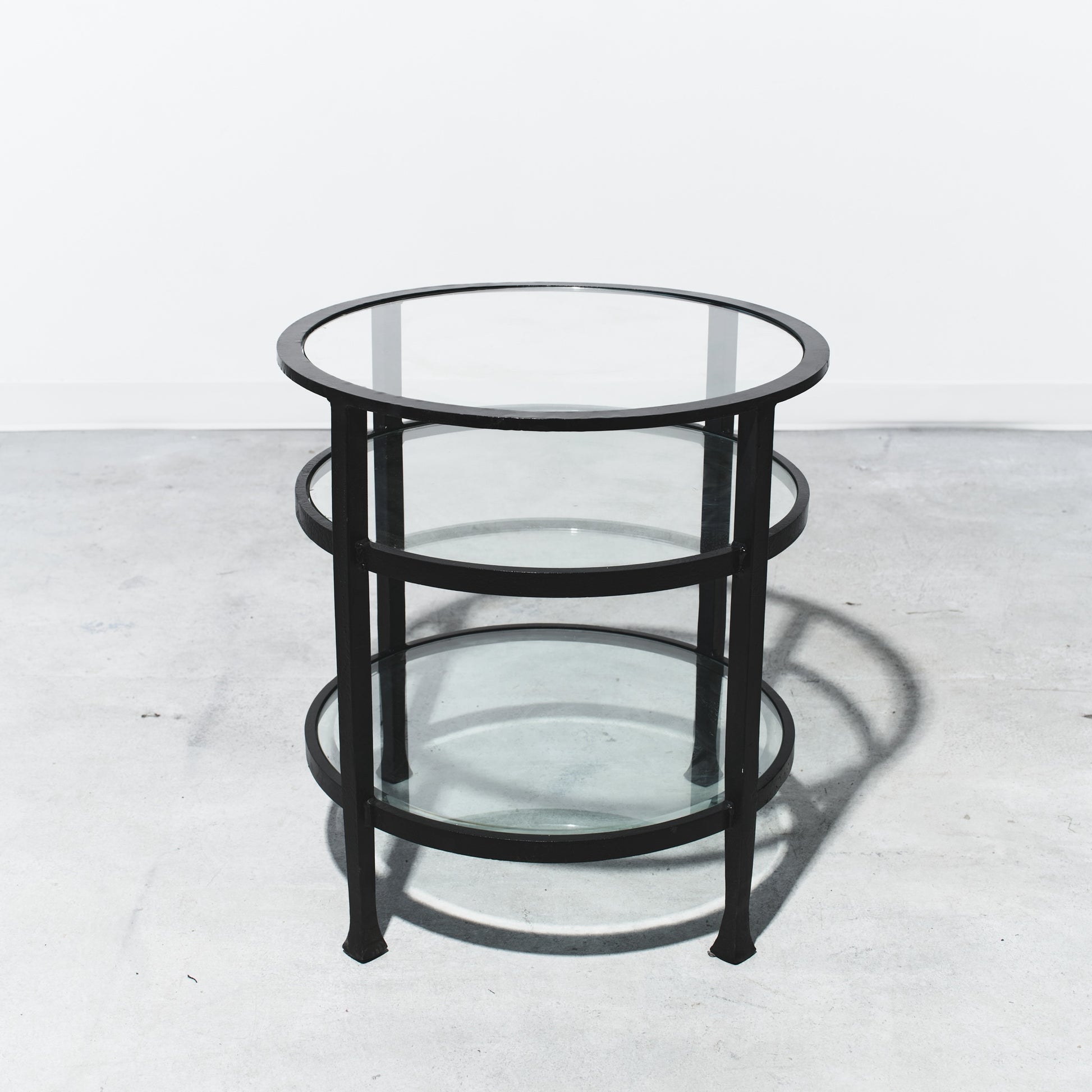 Round glass table with black metal frame on a white background
