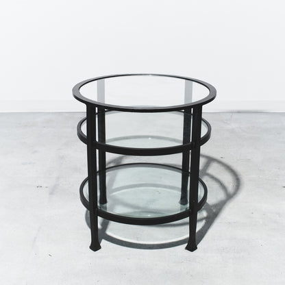 Round glass table with black metal frame on a white background