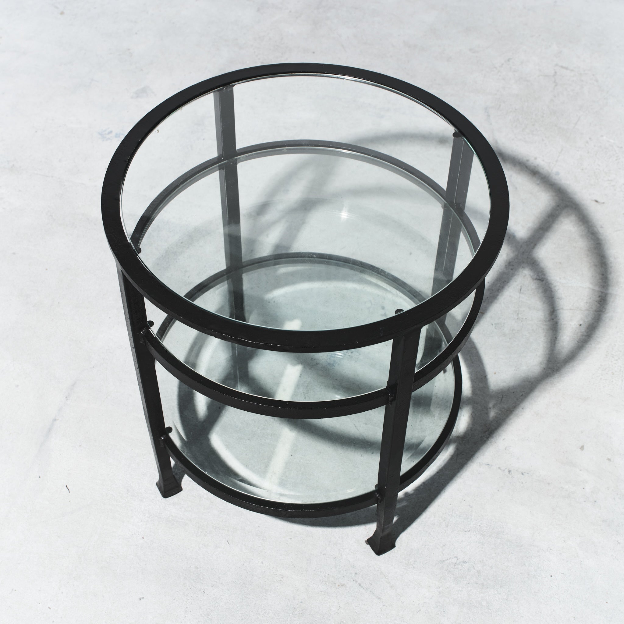 Round glass table with black metal frame on a light gray background