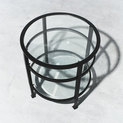 Round glass table with black metal frame on a light gray background