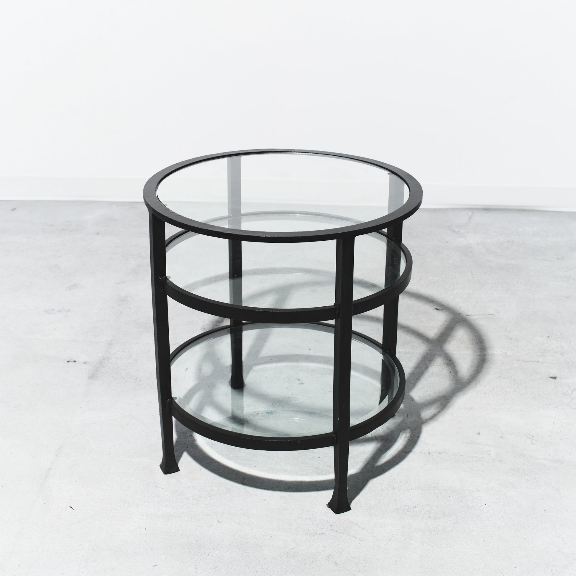 Round glass table with black metal frame on a white background