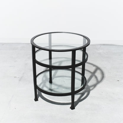 Round glass table with black metal frame on a white background