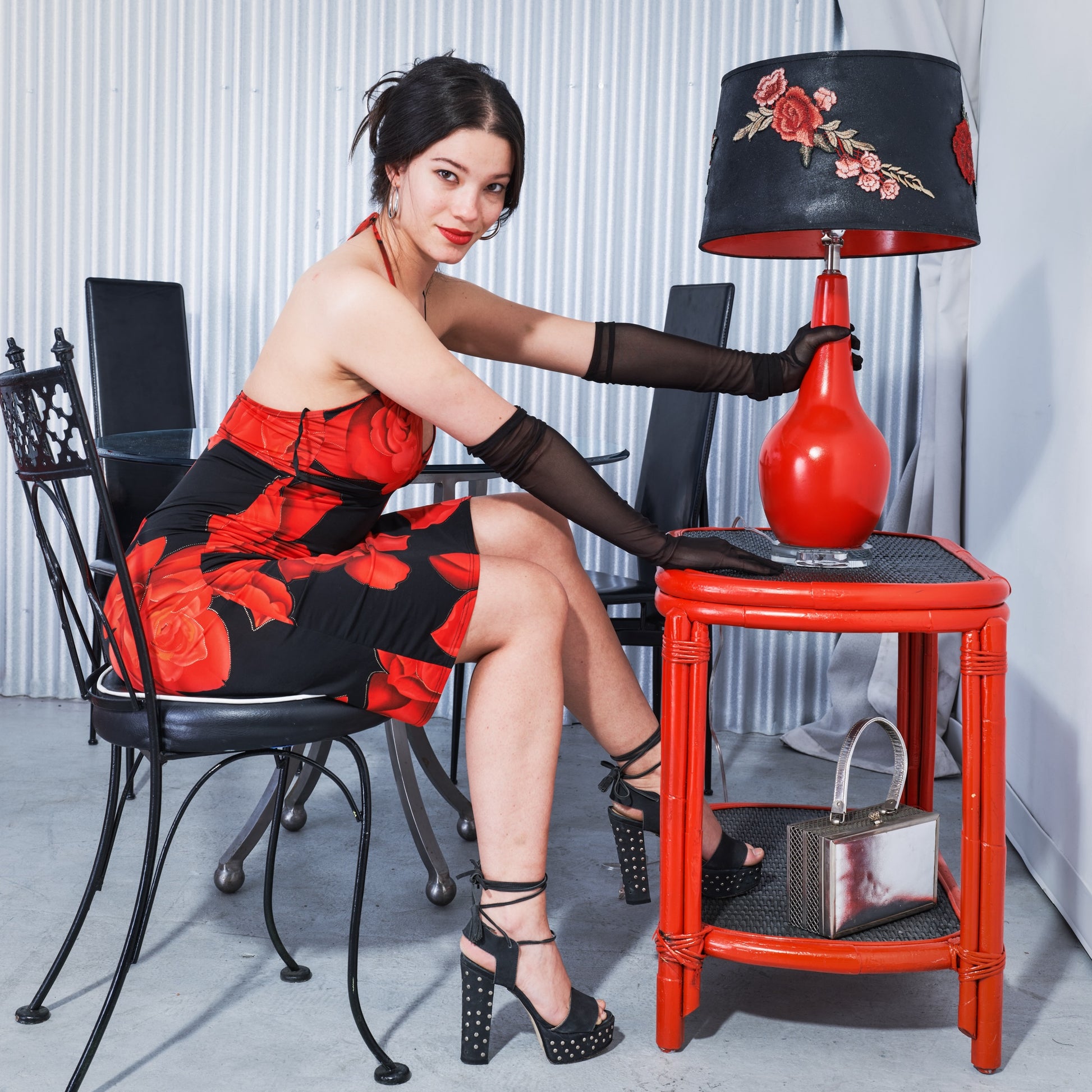 Woman in a red and black dress interacting with a red lamp on a matching table.