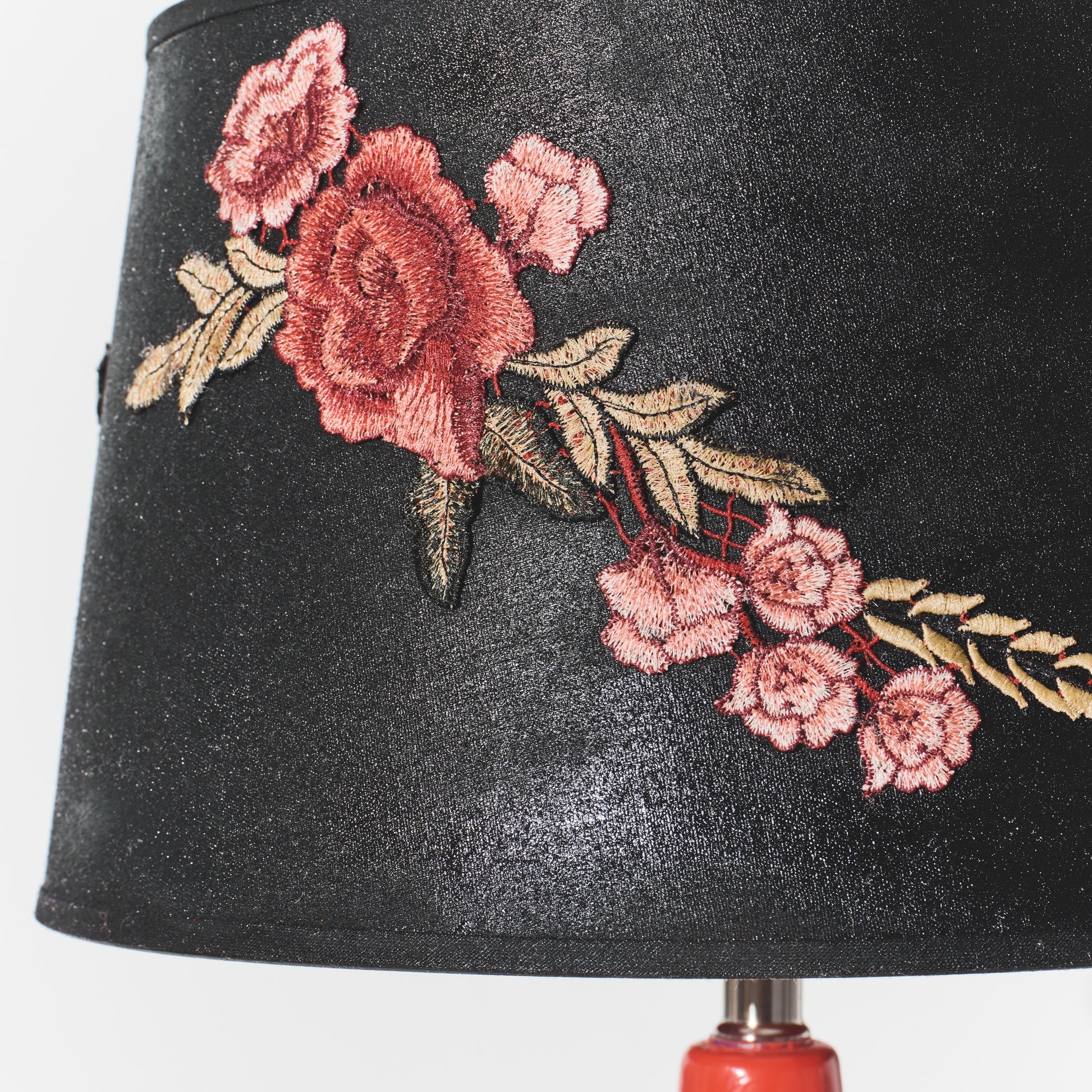 Black lampshade with pink floral embroidery on a white background