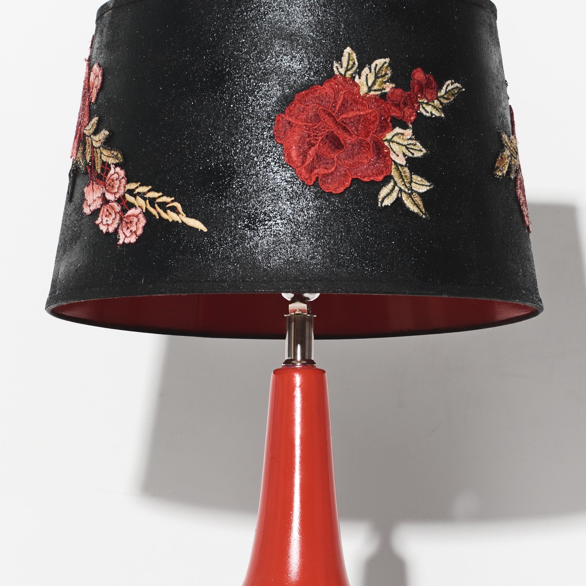 Black lampshade with floral embroidery on a red base