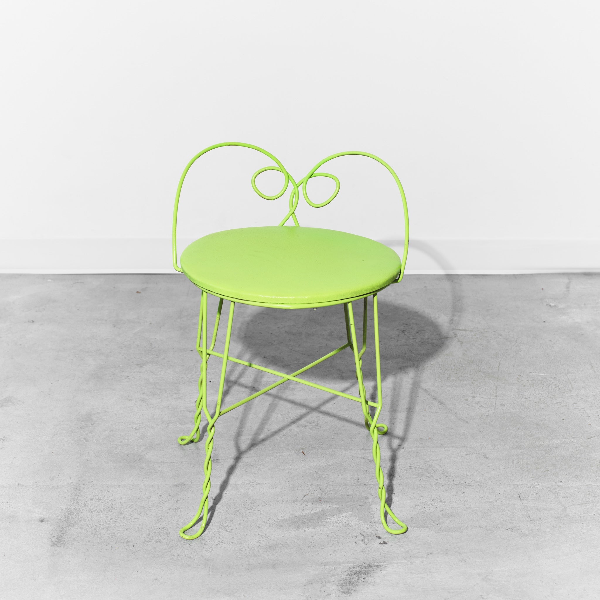 Green metal chair on a gray concrete floor