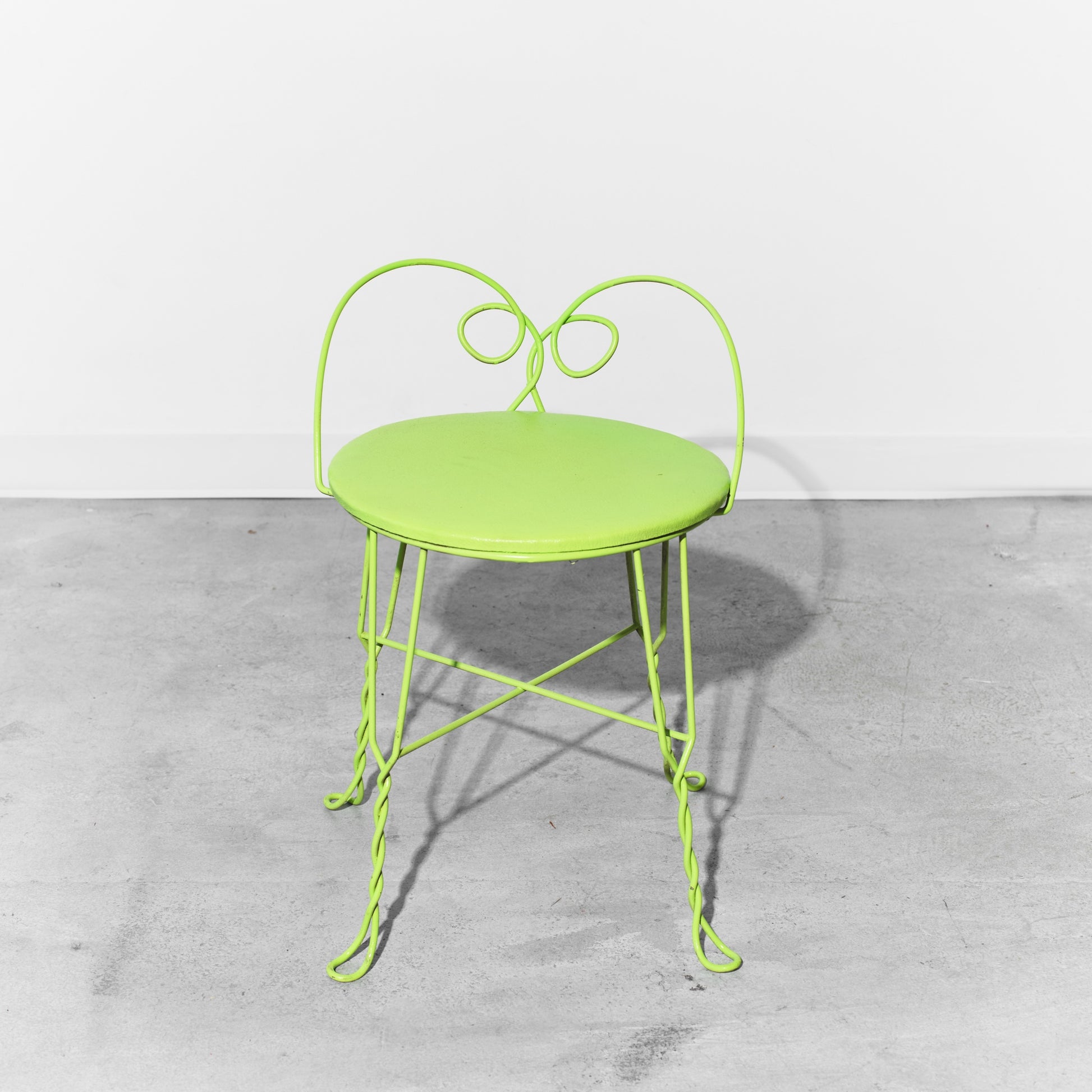 Green metal chair on a gray concrete floor
