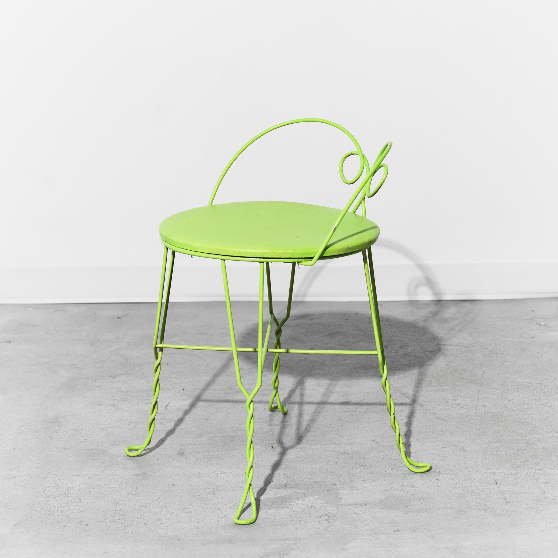Green metal chair on a gray floor with a white background
