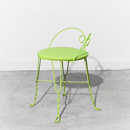Green metal chair on a gray floor with a white background