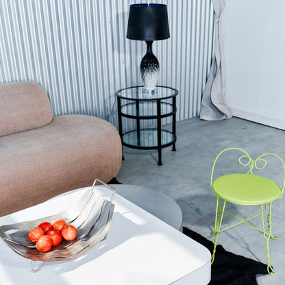 Modern living room with a beige sofa, glass table, black lamp, and green chair.
