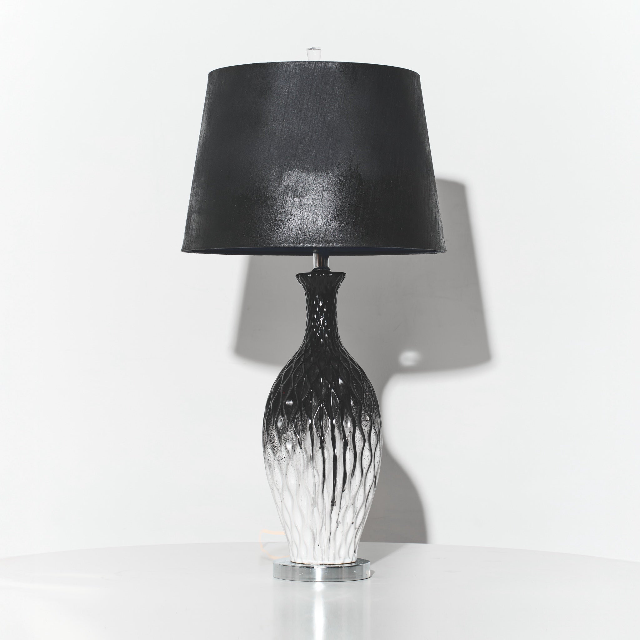 Table lamp with black shade and decorative base on a white background