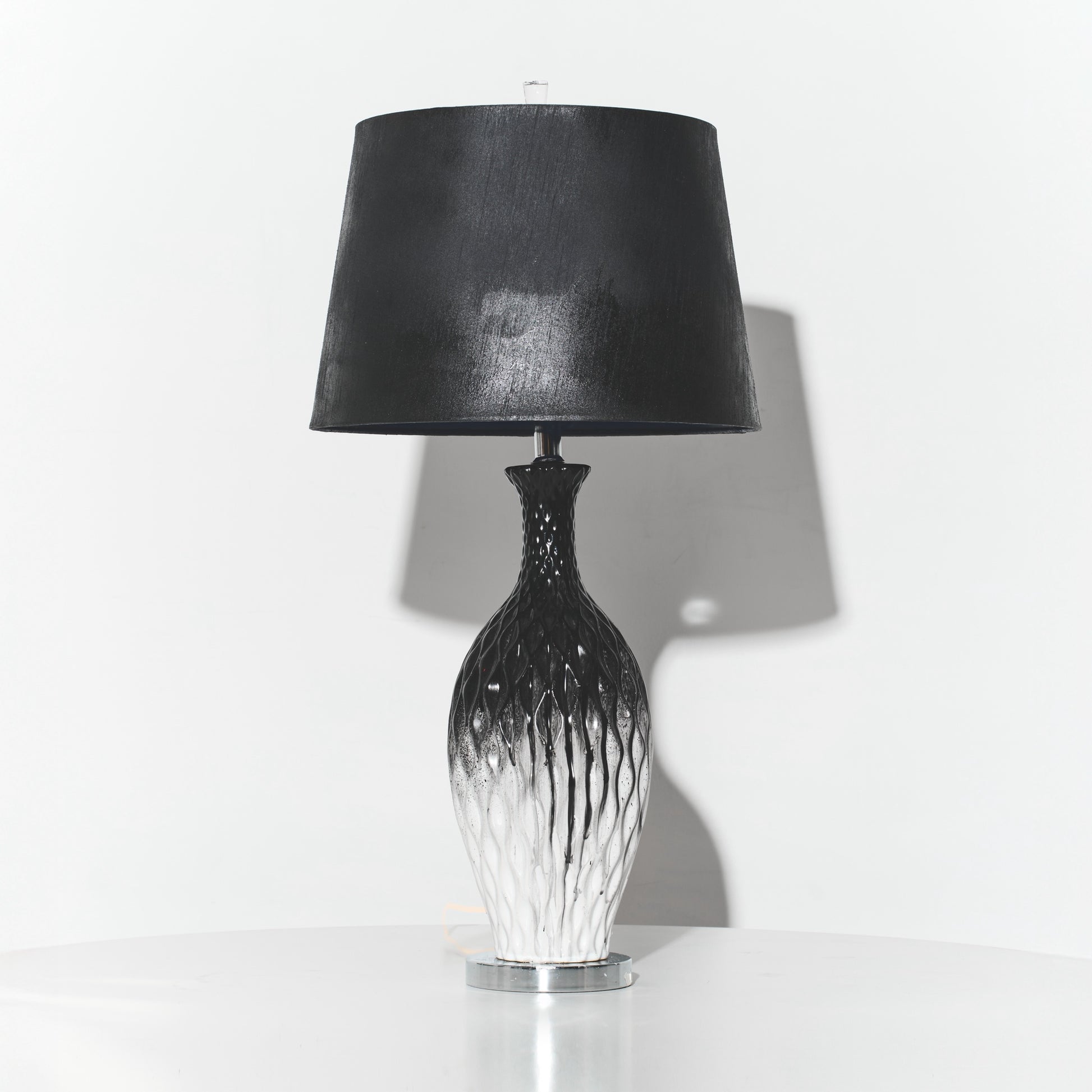 Table lamp with black shade and decorative base on a white background