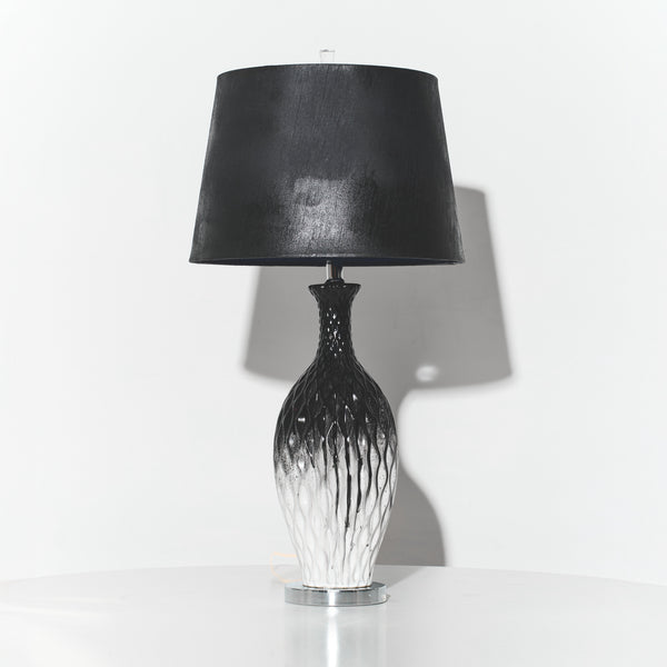 Table lamp with black shade and decorative base on a white background