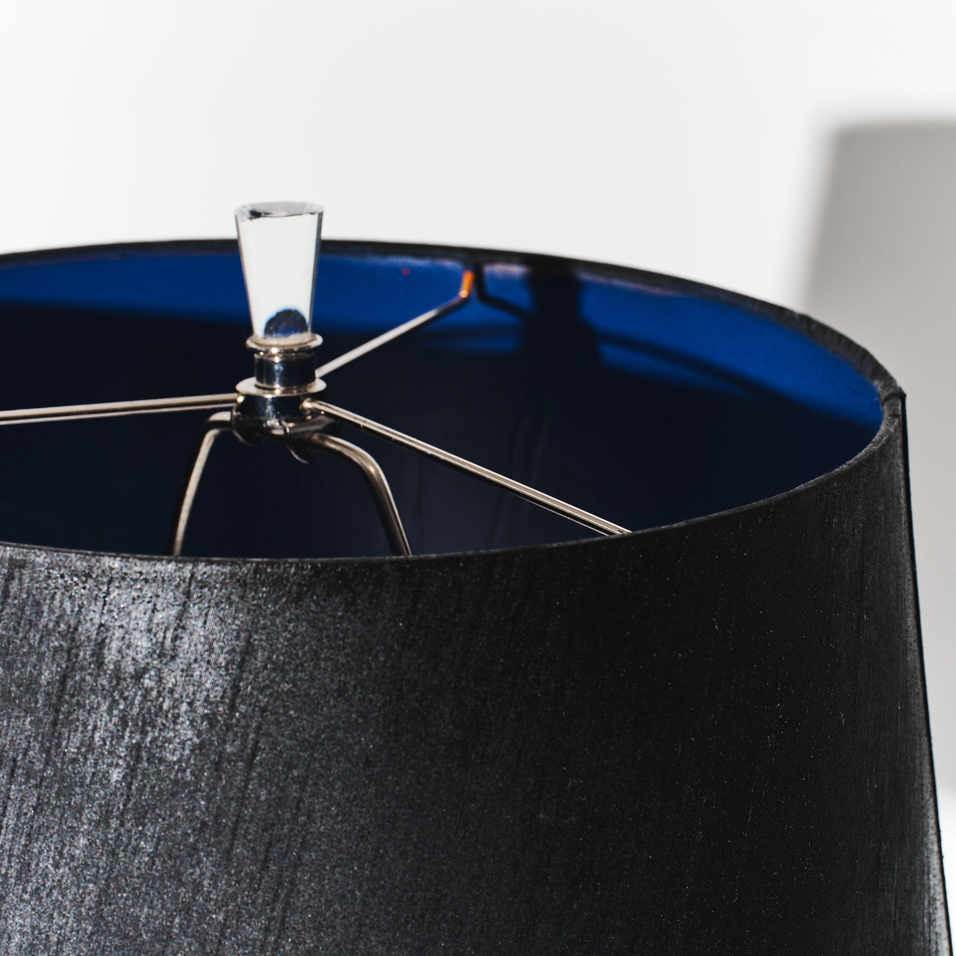 Close-up of a black lampshade with a metallic fitting on a white background