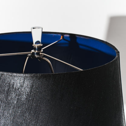 Close-up of a black lampshade with a metallic fitting on a white background