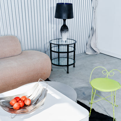 Modern living room with a beige sofa, glass table, black lamp, and green chair.