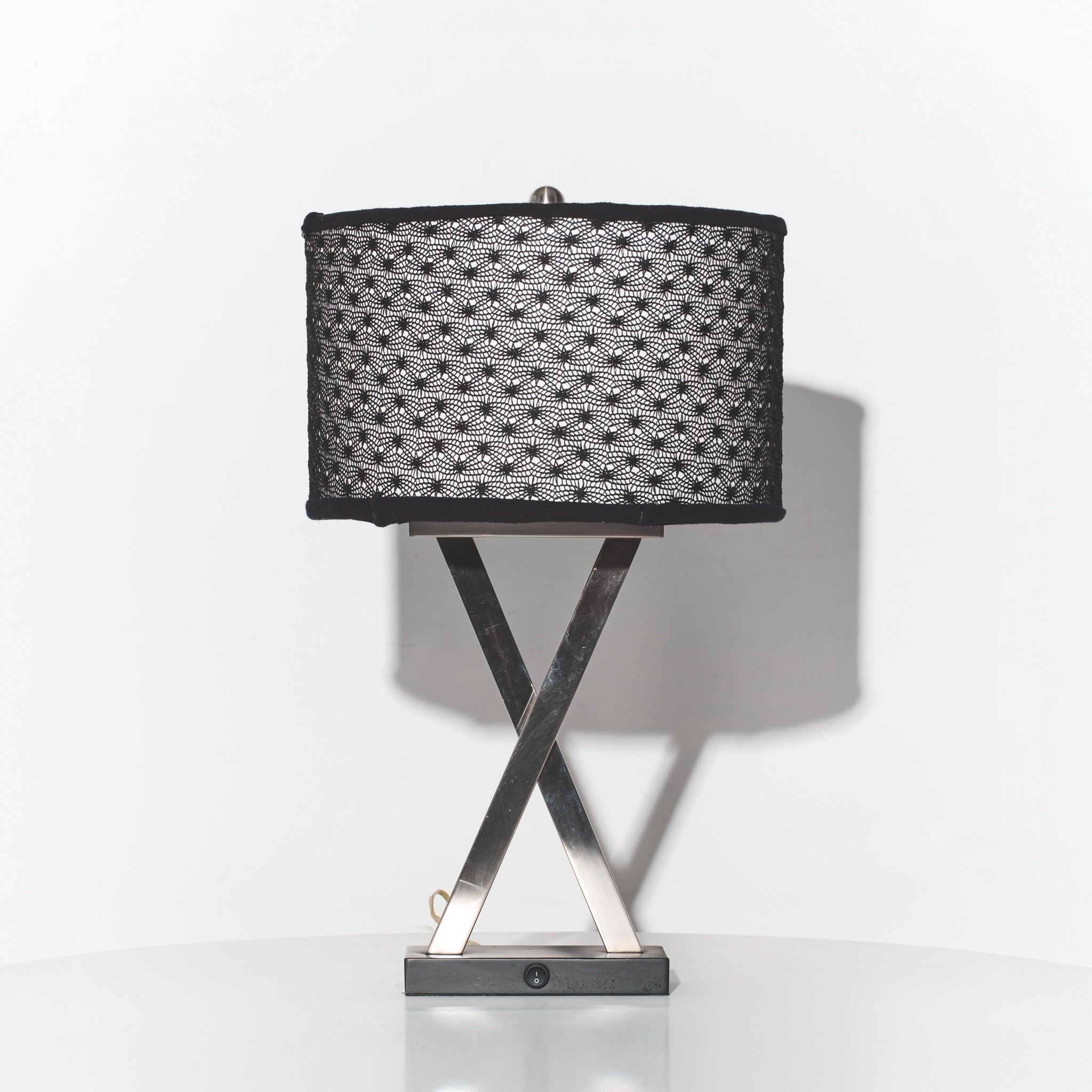 Table lamp with black textured shade and metallic base on a white background