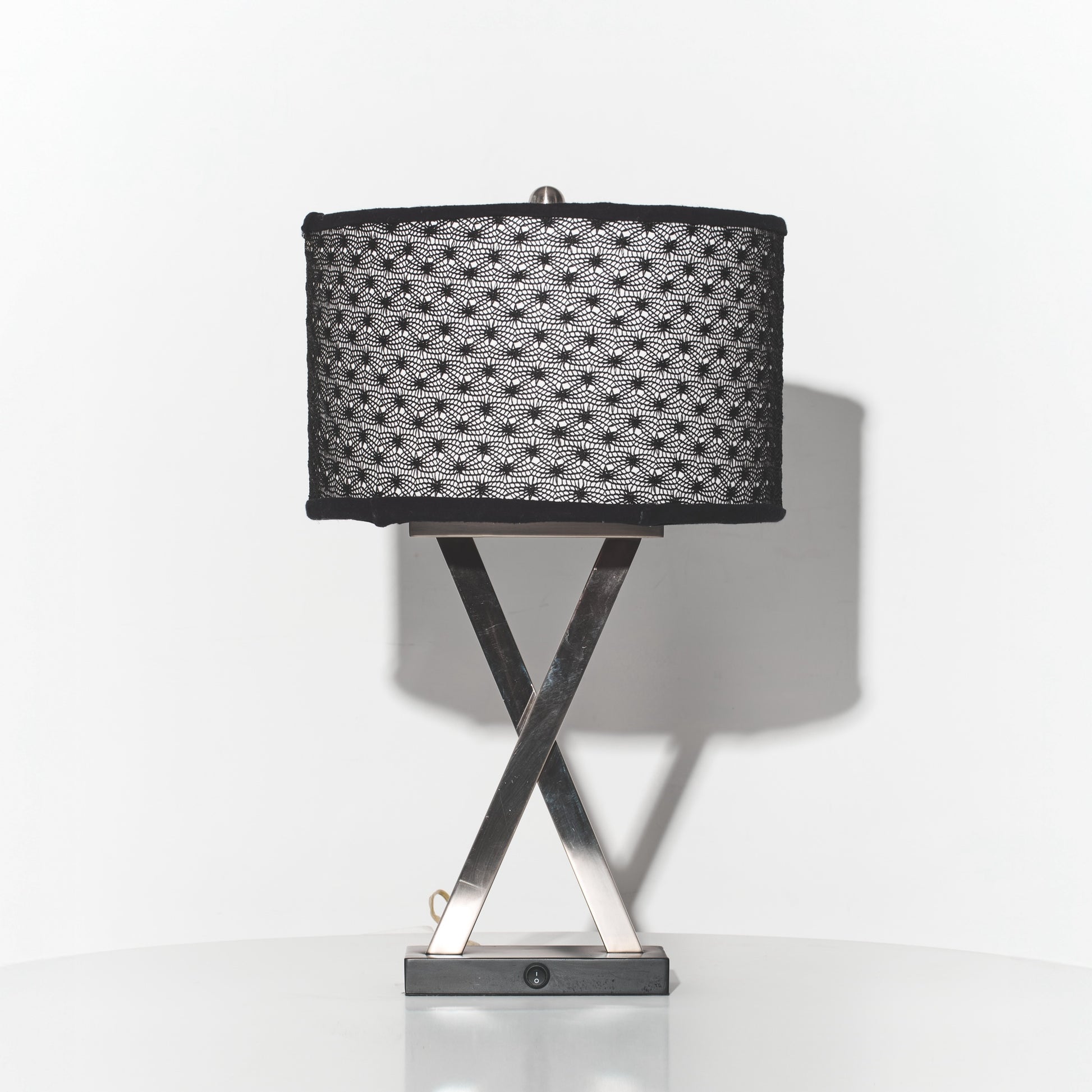 Table lamp with black textured shade and metallic base on a white background