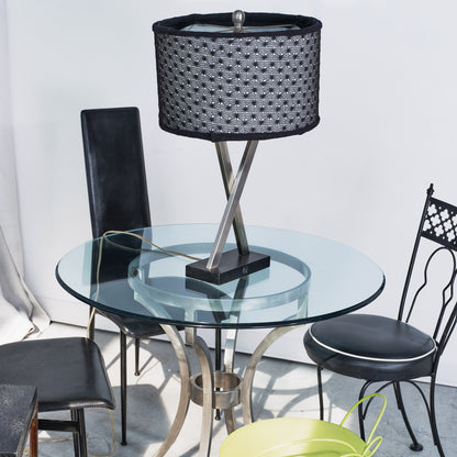 Glass dining table with black chairs and a decorative lamp on a light background