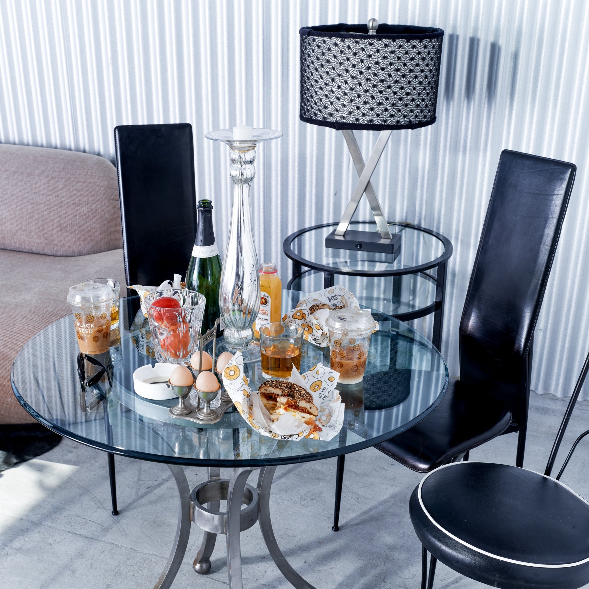Round glass table with drinks and snacks in a modern living room setting.