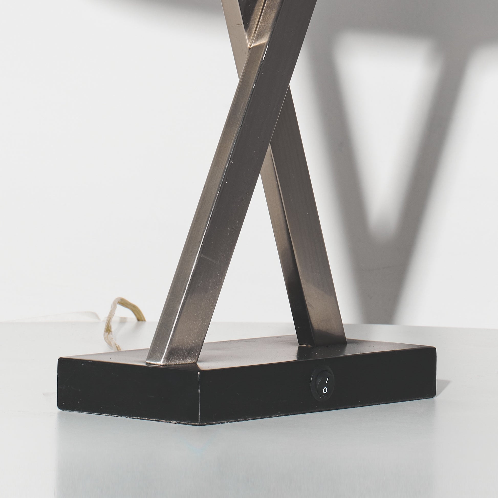 Modern table lamp with crossed metal legs on a white surface