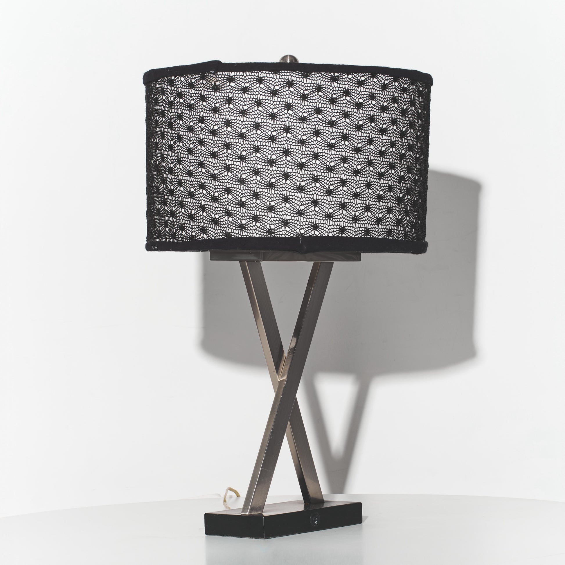 Table lamp with black woven shade and metal base on a white background