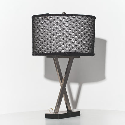 Table lamp with black woven shade and metal base on a white background