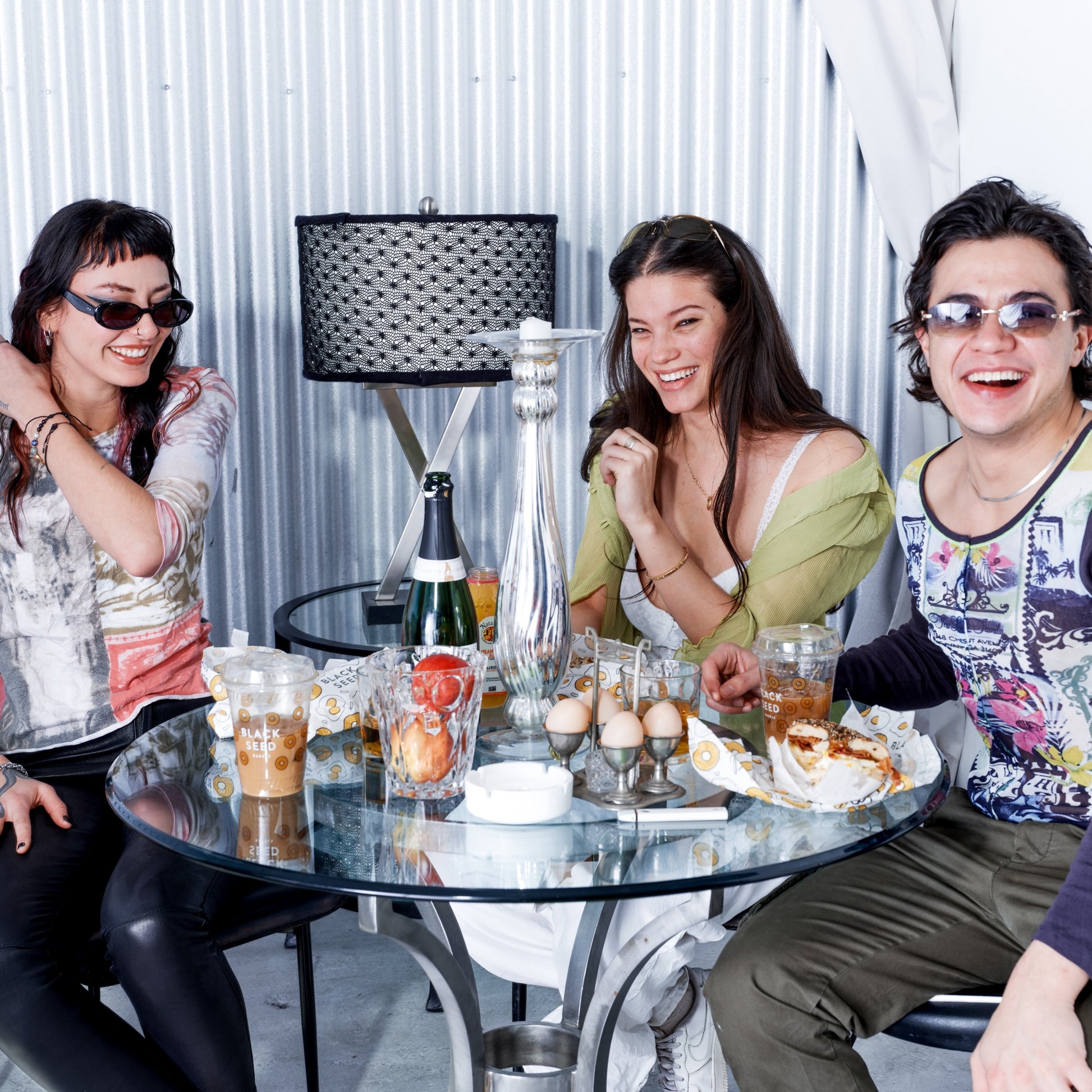 Three people sitting around a table with drinks and food, smiling.