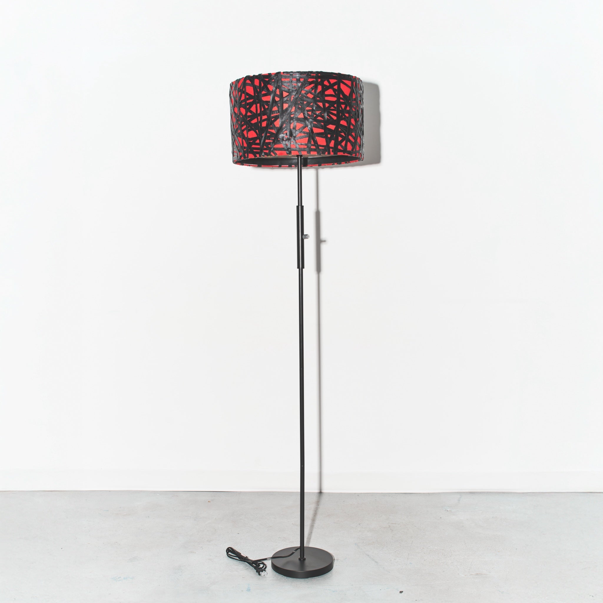 Floor lamp with a red and black patterned shade on a white background