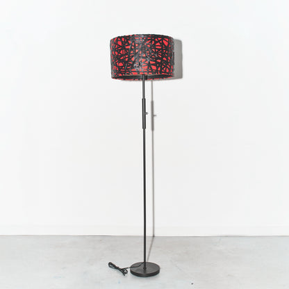 Floor lamp with a red and black patterned shade on a white background