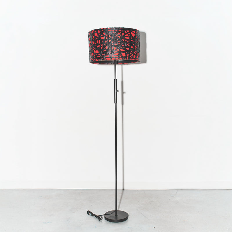 Floor lamp with a red and black patterned shade on a white background