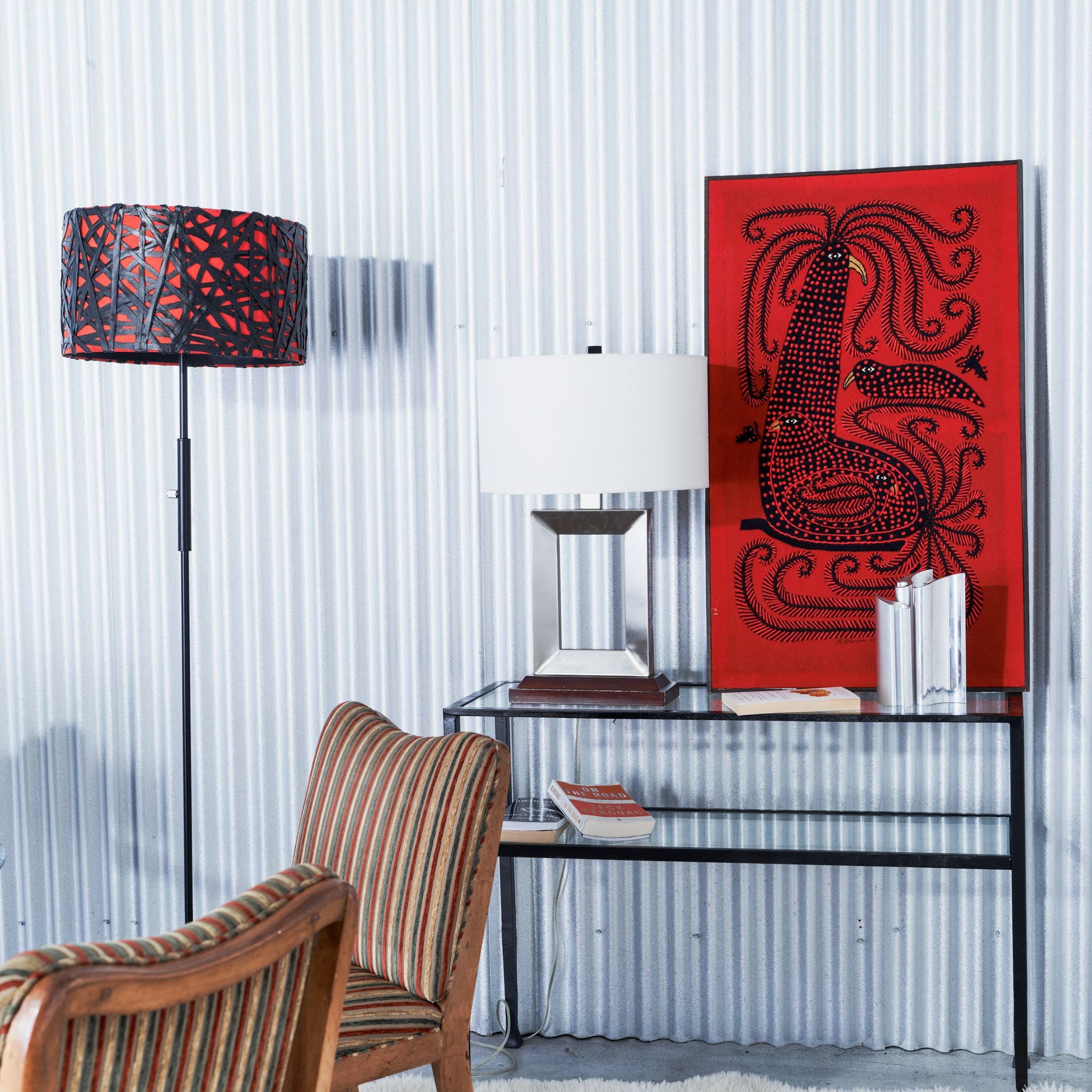 Modern interior with a glass desk, striped chair, and red abstract artwork.
