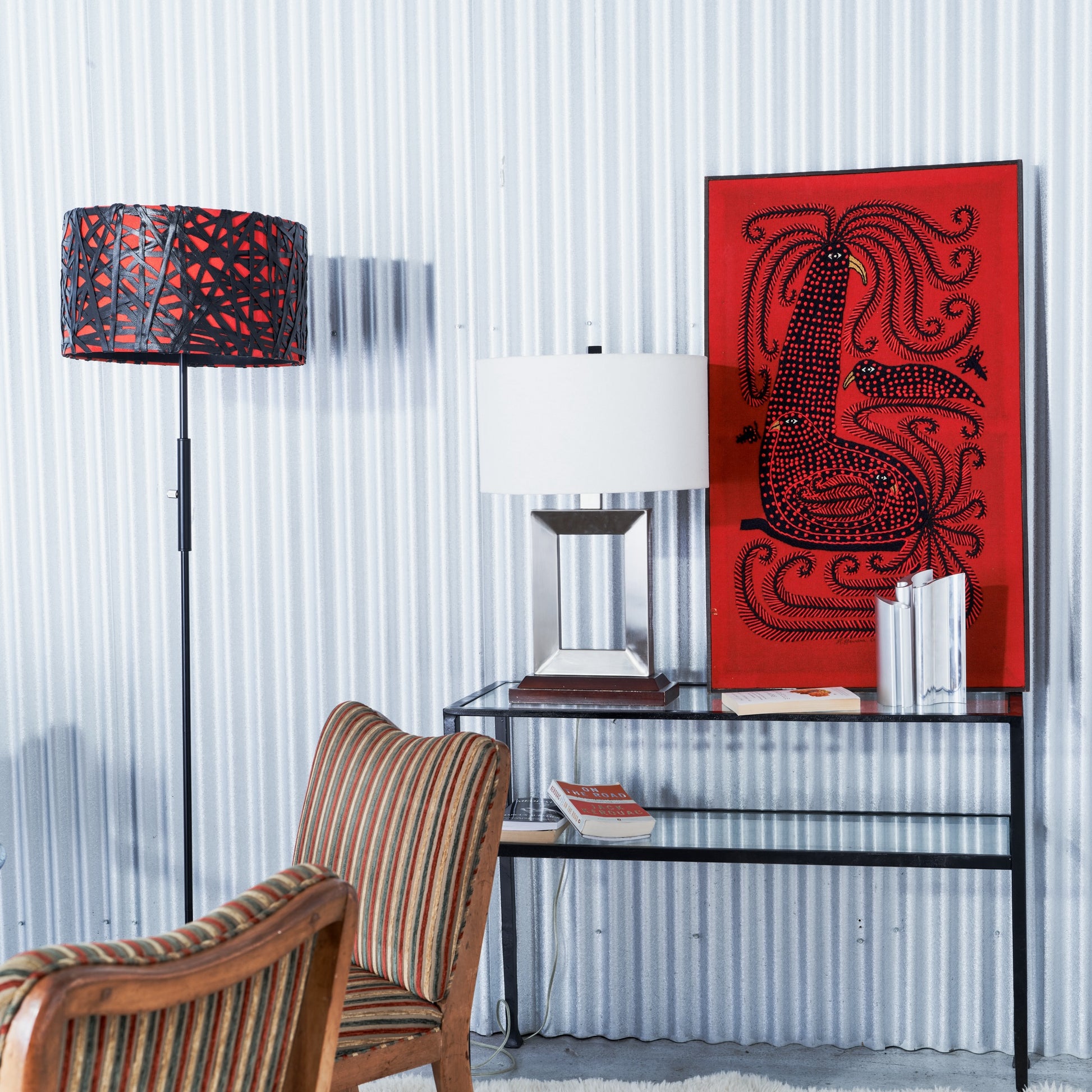 Modern interior with a glass desk, striped chair, and red abstract artwork.