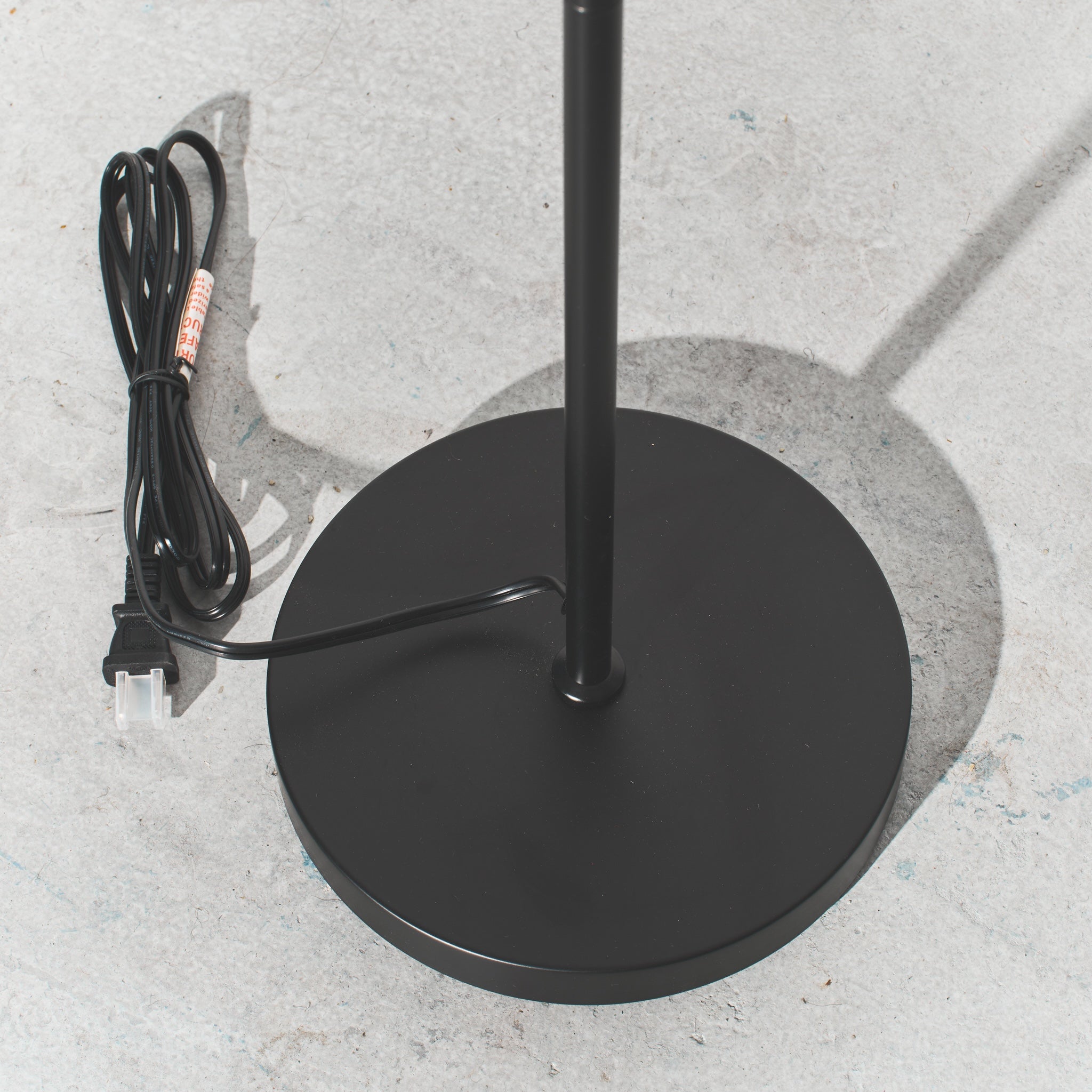 Black outdoor umbrella base with power cord on a concrete surface