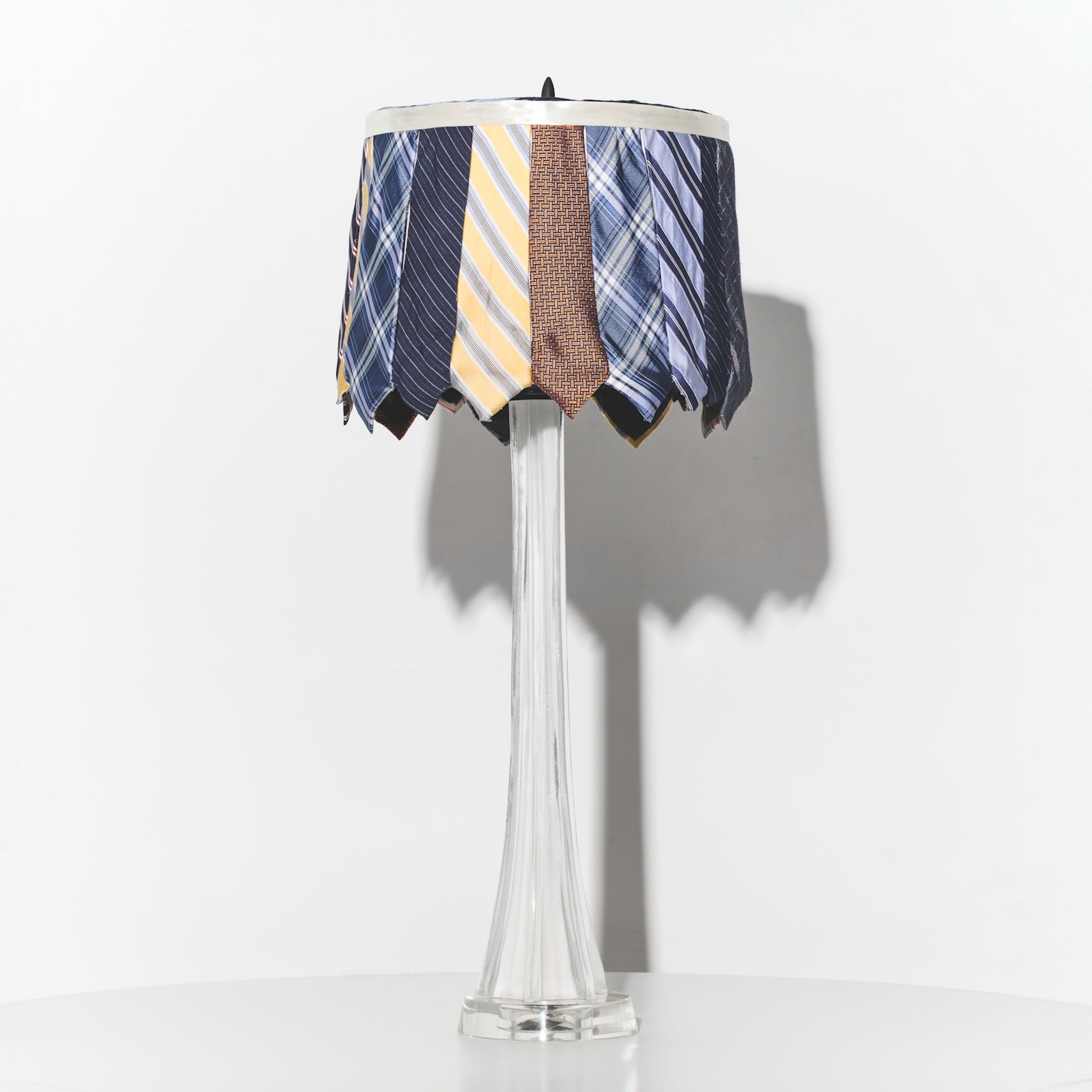 Lamp with a decorative shade made from ties on a white background