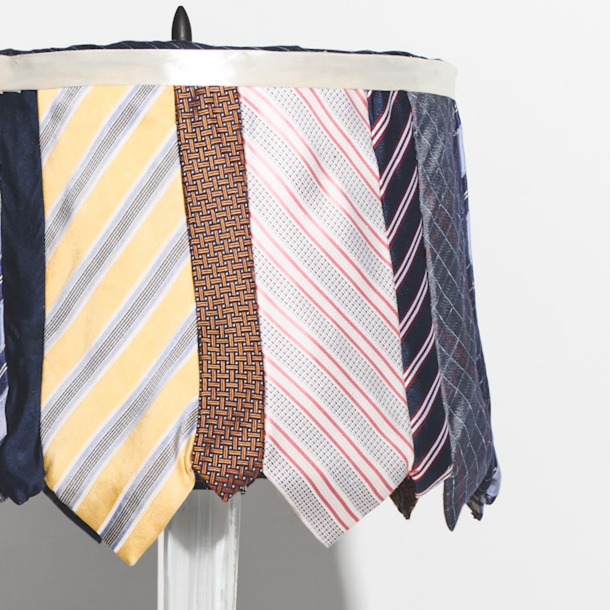 Collection of various patterned ties on a lamp against a white background