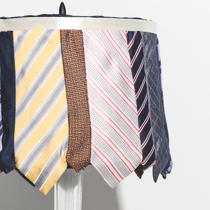 Collection of various patterned ties on a lamp against a white background