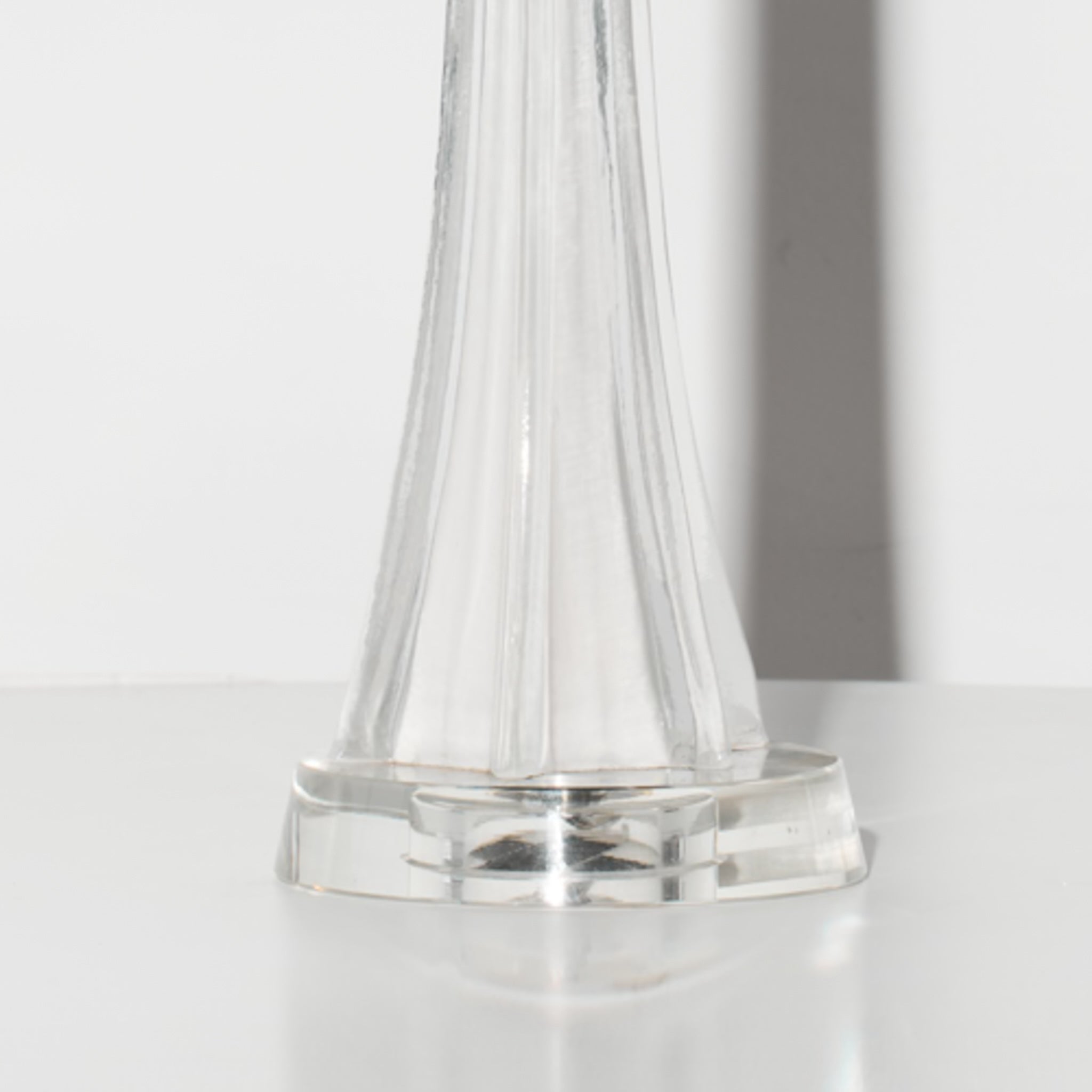 Clear glass Lamp base on a white surface with a neutral background