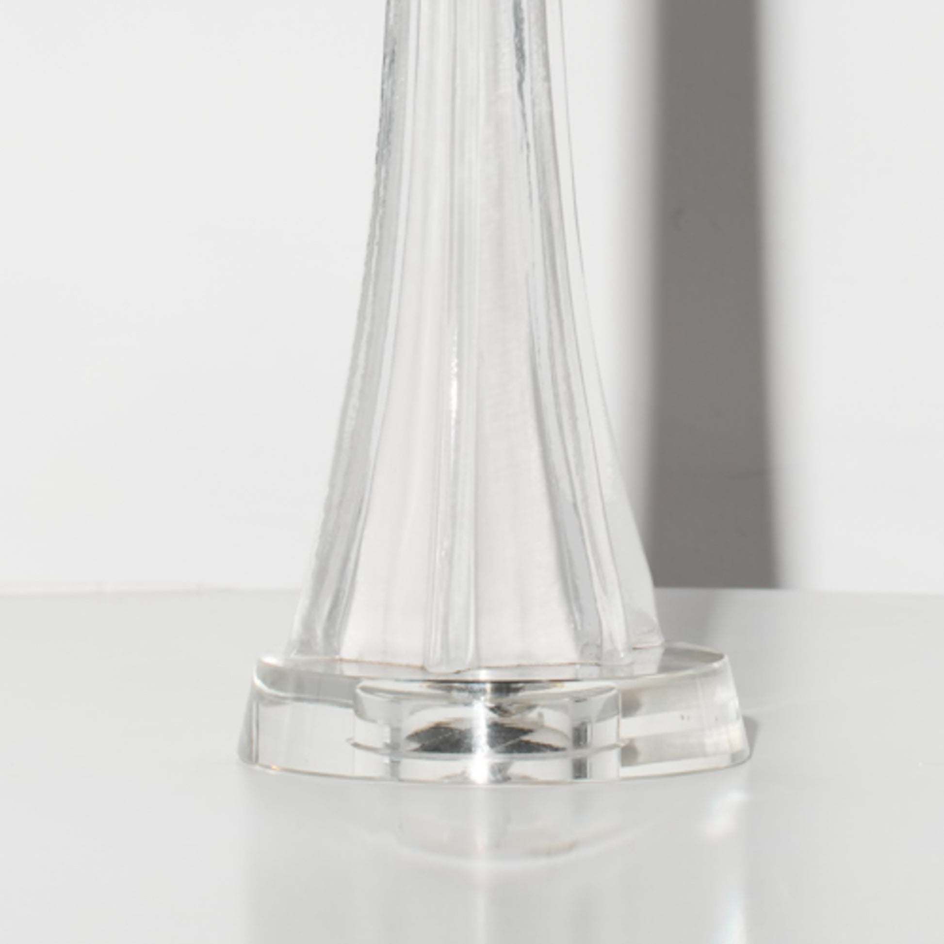 Clear glass Lamp base on a white surface with a neutral background