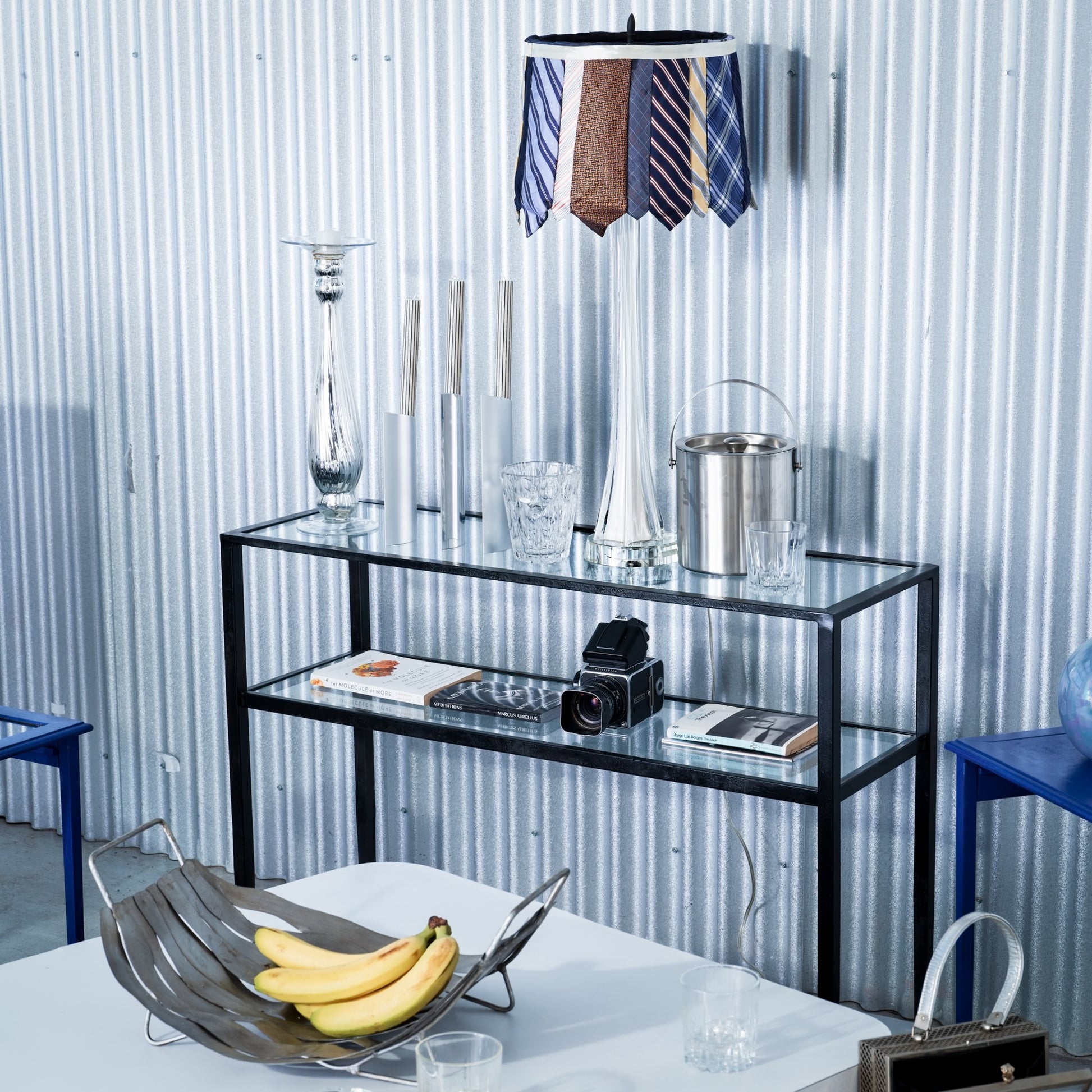 Modern interior with a glass console table against a corrugated metal wall.