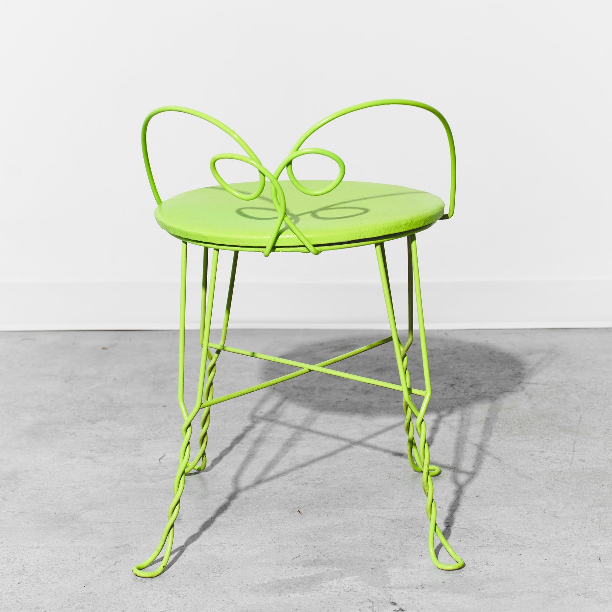 Neon green metal chair on a gray concrete floor with a white background