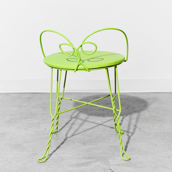 Neon green metal chair on a gray concrete floor with a white background
