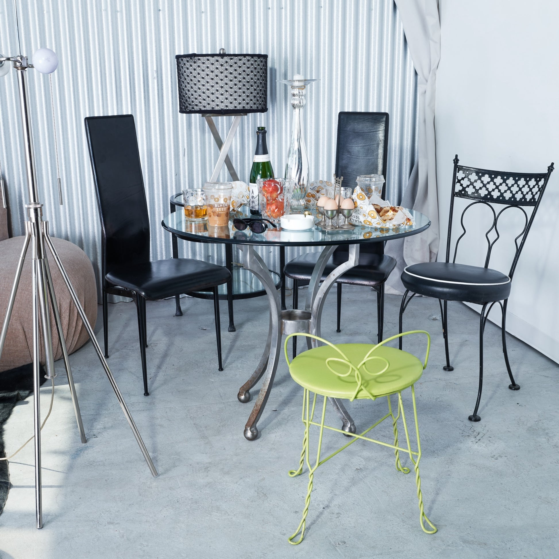 Outdoor dining setup with black chairs, a glass table, and a green chair.