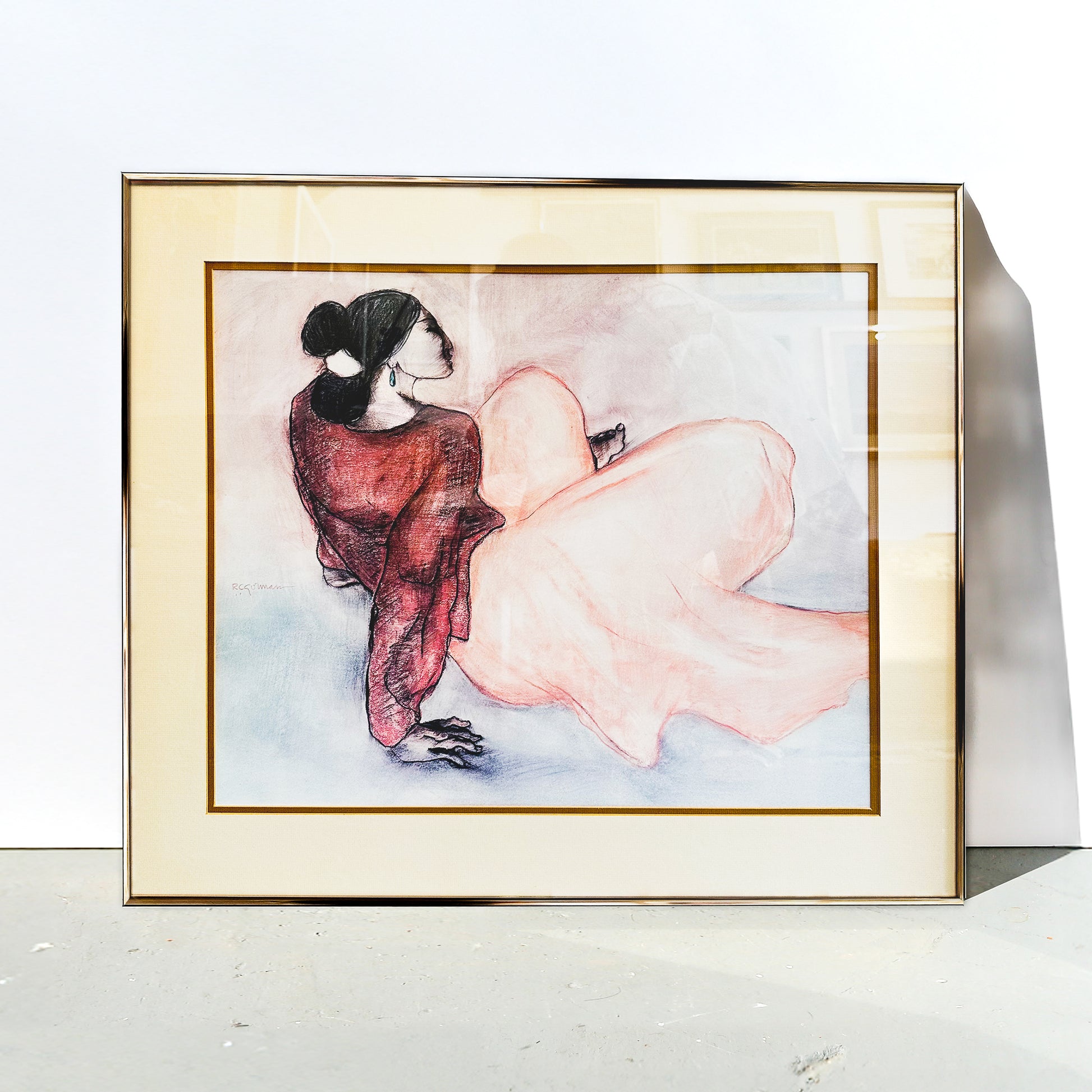 Framed artwork of a woman in a red dress sitting on a white surface