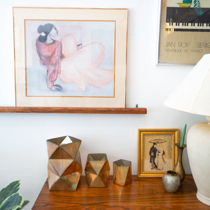 Decorative items on a wooden shelf with framed art in the background