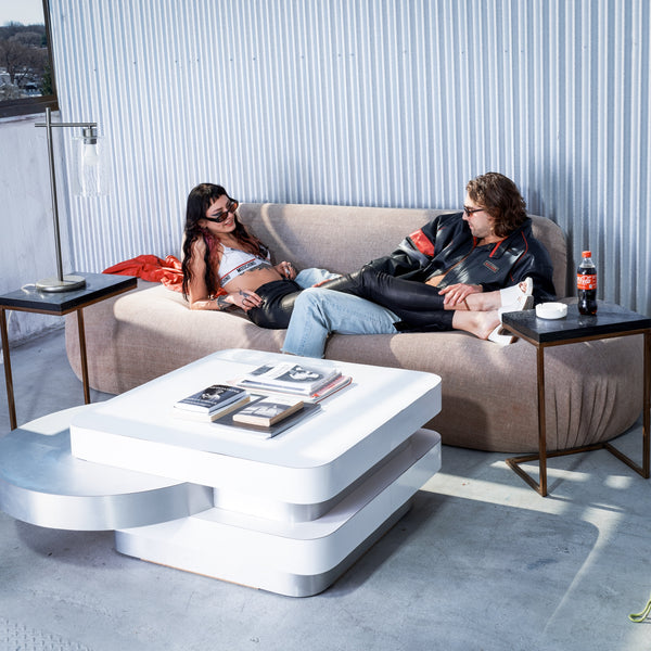 Two people sitting on a modern sofa with a white coffee table in a stylish room.