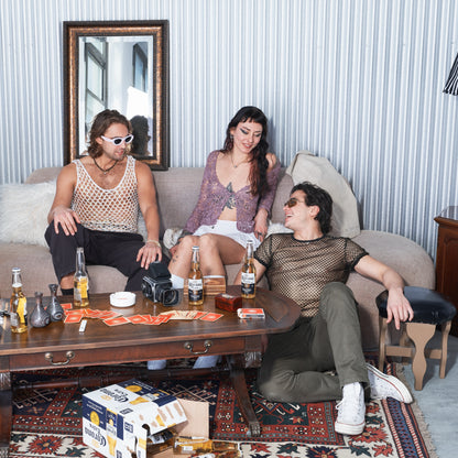 Three people sitting on a couch in a living room with drinks and snacks.
